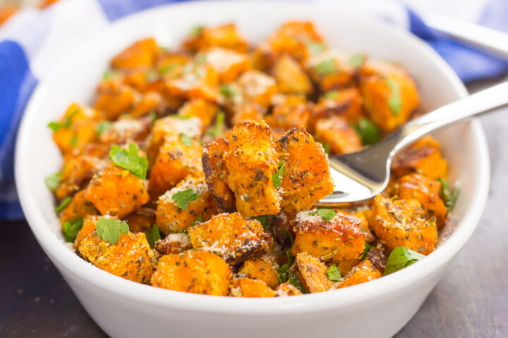 sweet potatoes in a white dish with a forkful showing a bite