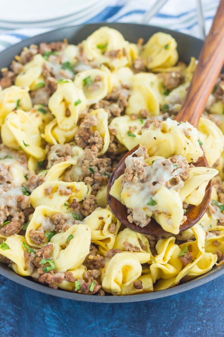 pasta in a black skillet with a wooden spoon showing a spoonful