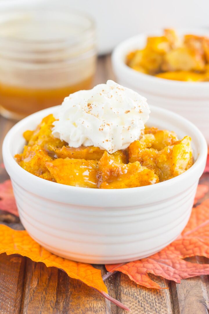 pumpkin bread pudding in a white bowl with a dollop of whipped cream