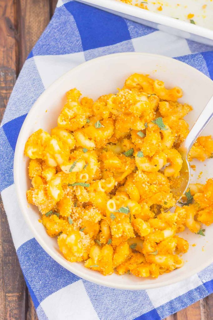 top down view of pumpkin pasta in a bowl with a blue gingham plaid napkin