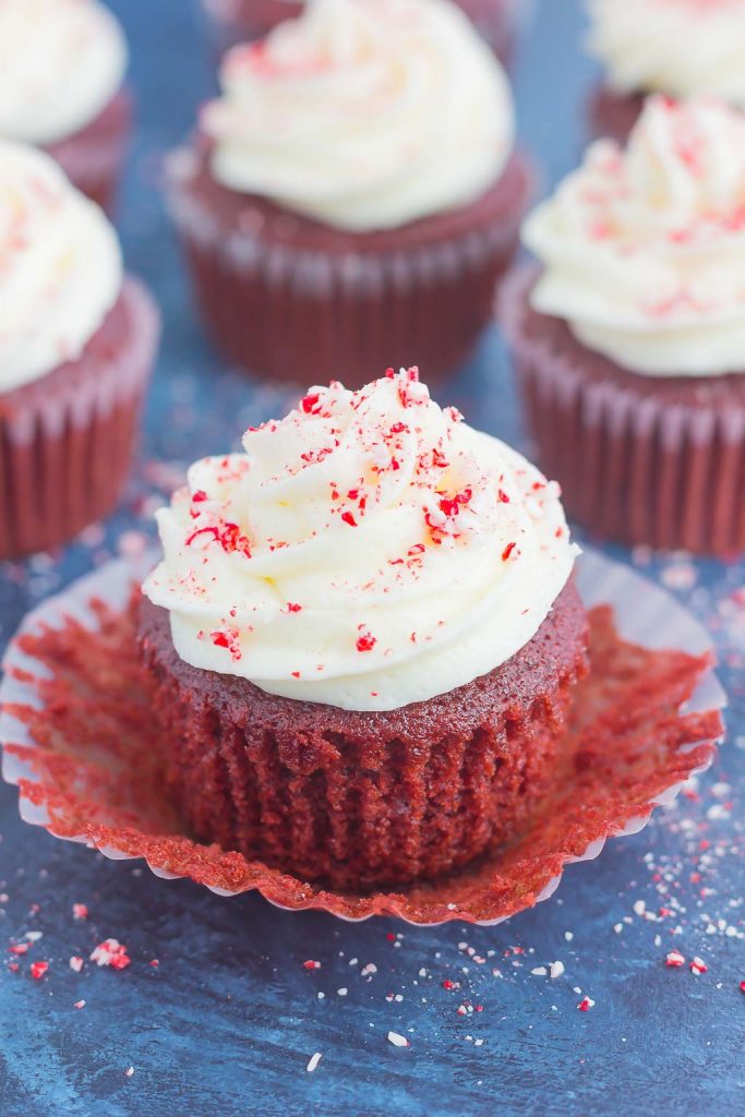 a red velvet cupcake with peppermint frosting in an unwrapped wrapper