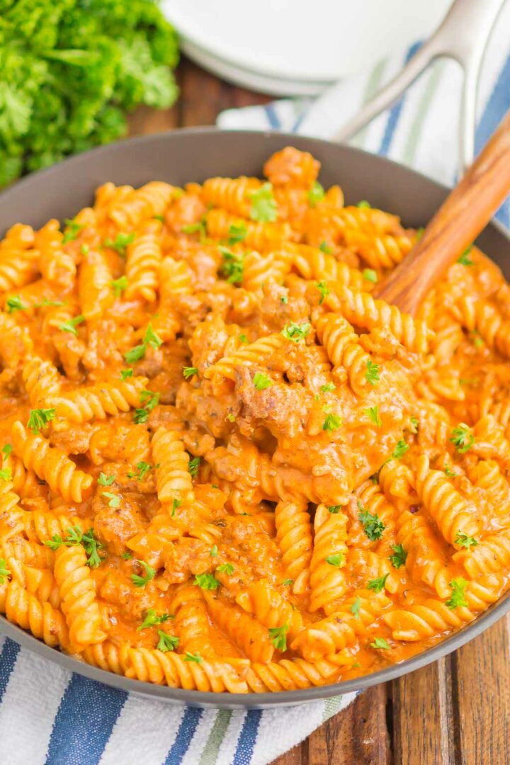 pasta in a black skillet with a wooden spoon