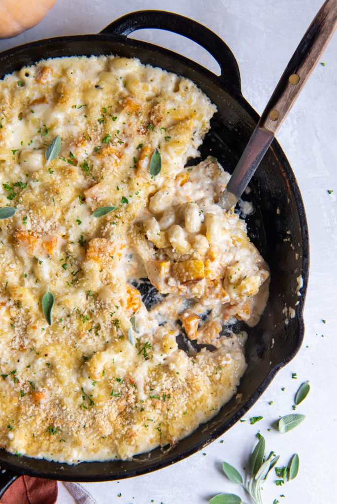 mac and cheese in a black skillet with a wooden spoon