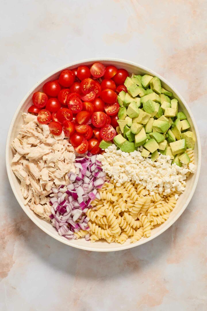 pasta salad ingredients in a white bowl