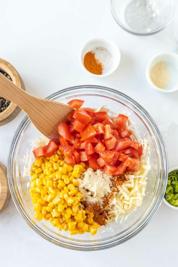 corn dip ingredients being mixed in a glass bowl