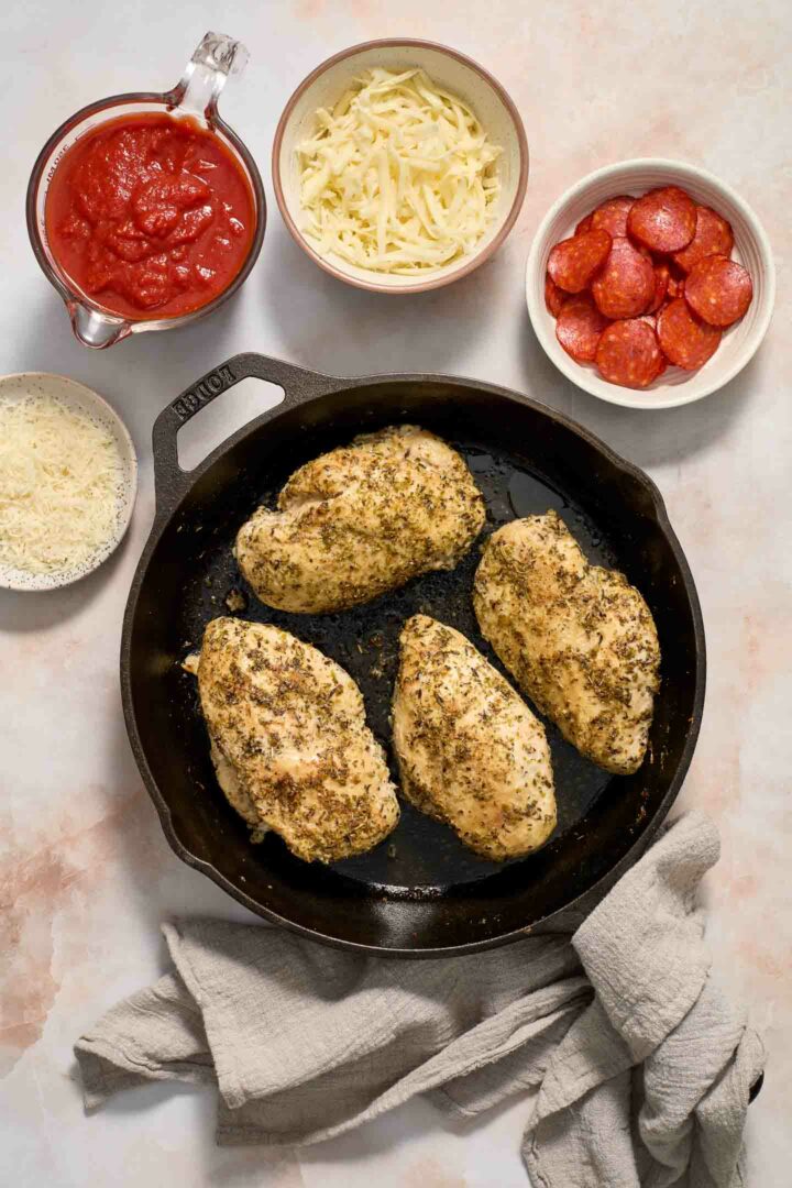 chicken seasoned in a black skillet with ingredients on the side