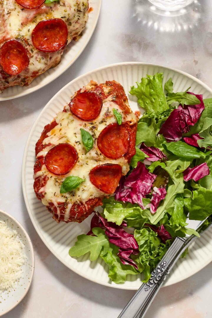 pizza chicken on a white plate with a green salad