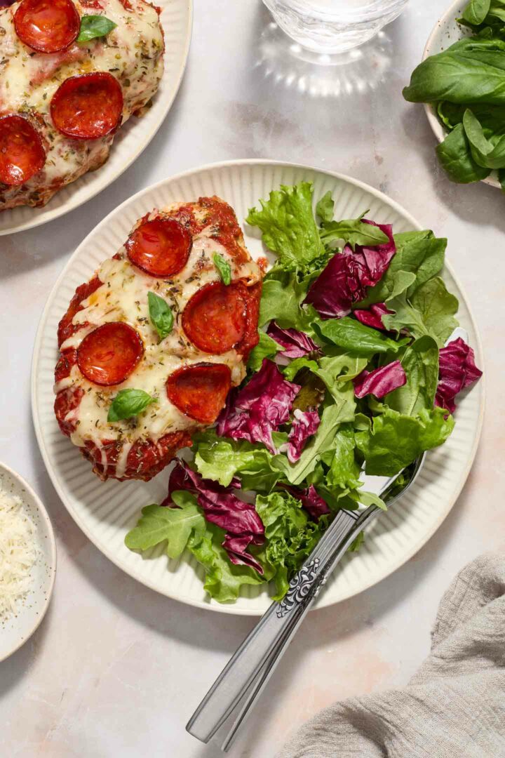 pizza chicken on a white plate with a green salad