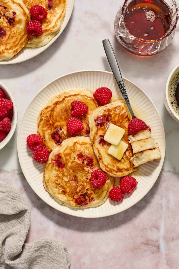 pancakes on a white plate with a bite of pancakes on a fork