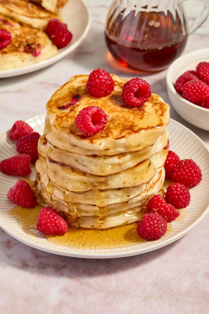 pancakes stacked on top of each other with raspberries and syrup