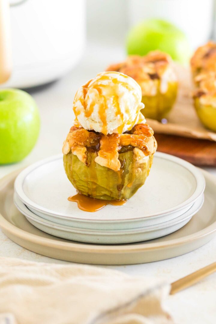 a baked apple with vanilla ice cream and caramel drizzle on a white plate