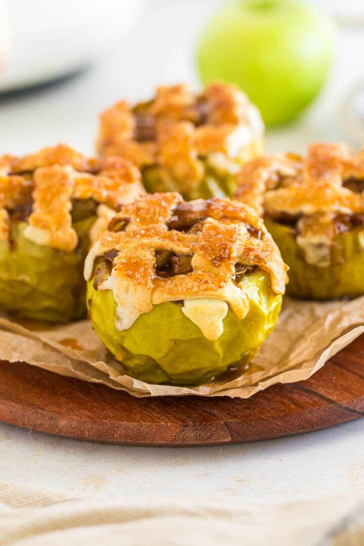 four baked apples on a wooden board