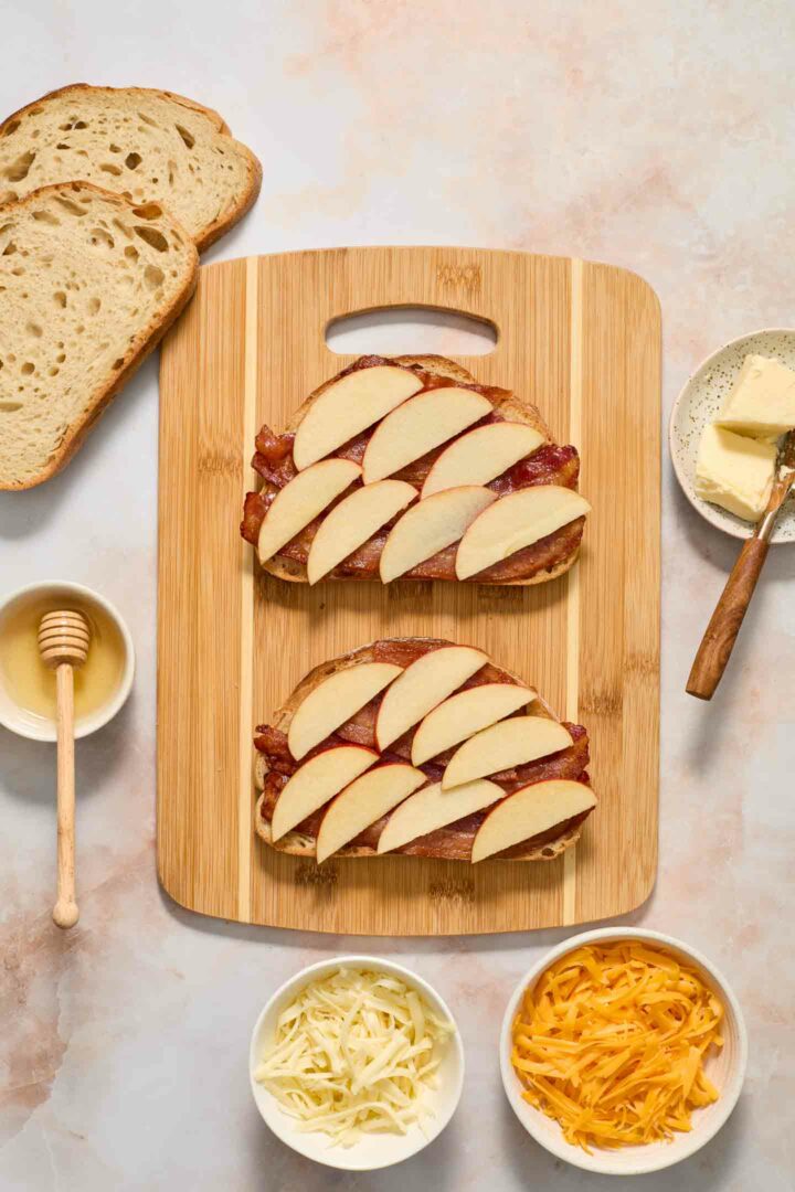 bread slices with bacon, honey, and apples on a cutting board