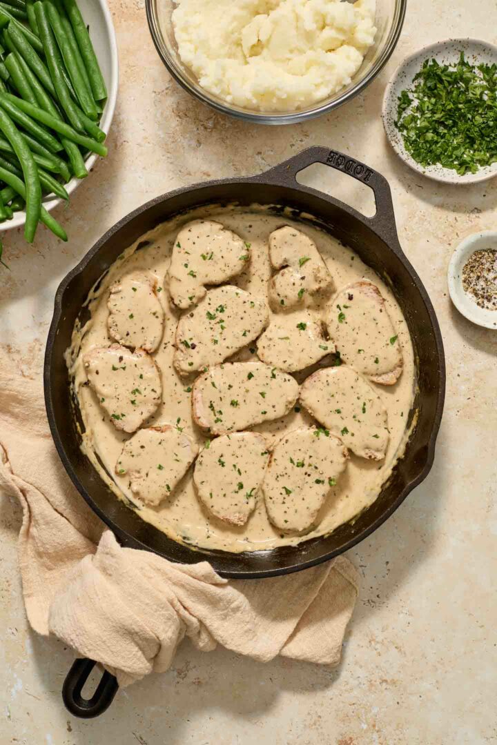 sliced pork tenderloin in cream sauce in a black skillet