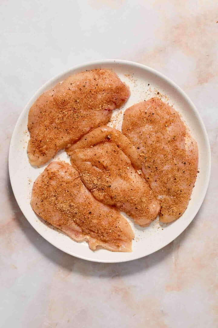 seasoned raw chicken on a white plate