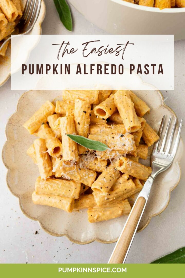 pumpkin alfredo pasta on a white plate with a silver fork next to another plate of pasta