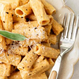 pumpkin alfredo pasta on a white plate with a silver fork