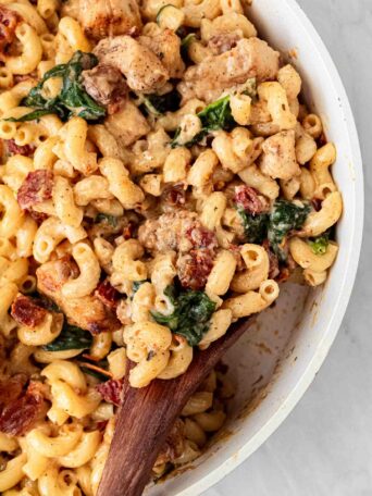 chicken mac and cheese in a white serving bowl with a wooden spoon