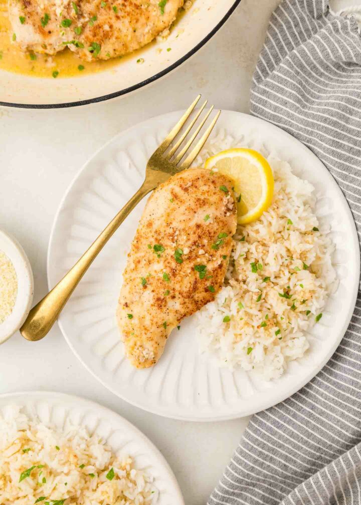 chicken on a white plate with rice and a fork