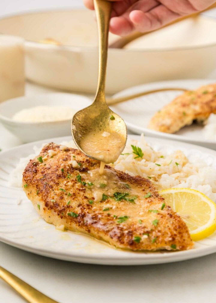 chicken on a white plate with rice and a spoon shown drizzling sauce over chicken