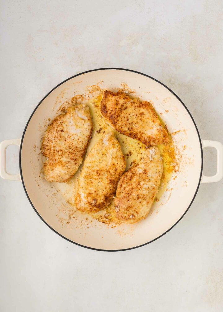 chicken seared and golden brown in a white skillet