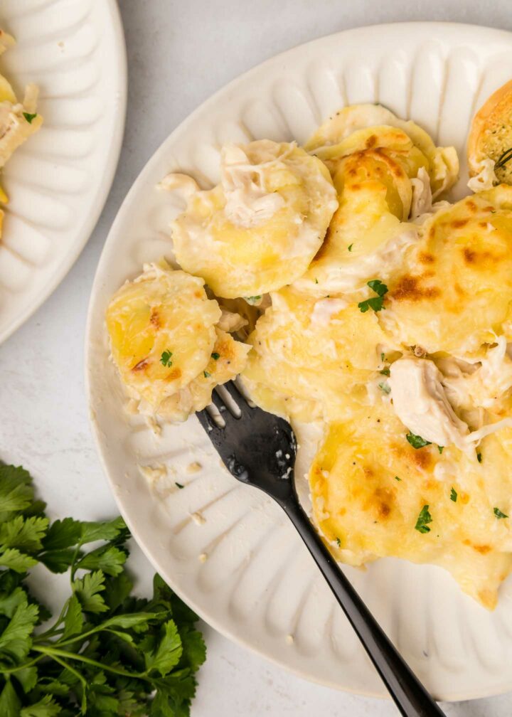 baked ravioli on a white plate with a black fork