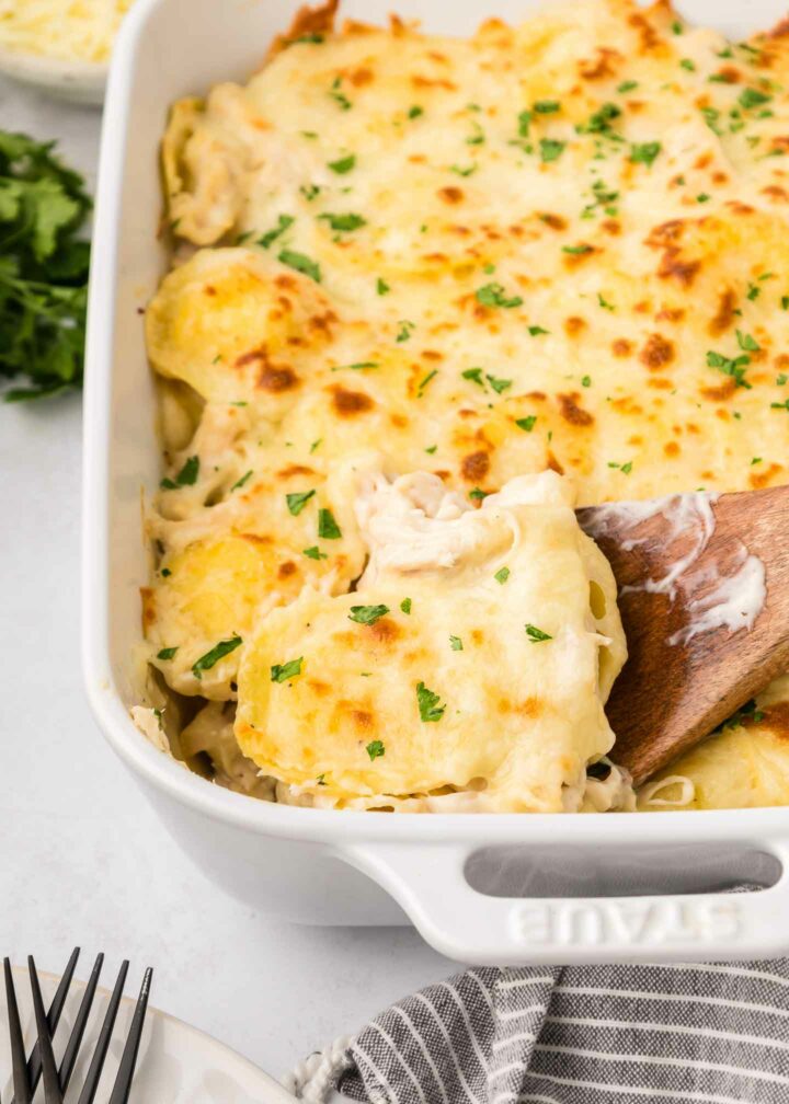 A golden, bubbly alfredo ravioli bake in a casserole dish, topped with melted cheese, fresh parsley, and creamy sauce. Perfect for showcasing this delicious baked ravioli recipe!