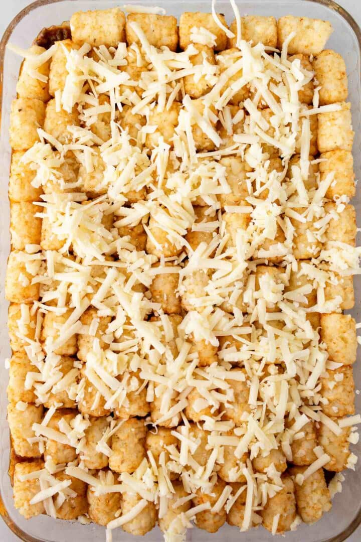 casserole in a dish with tater tots and shredded cheese