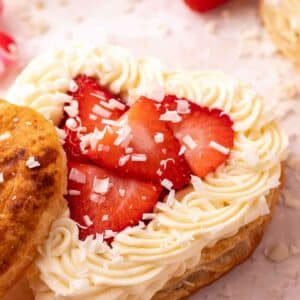 heart puff pastry with white chocolate mousse and sliced strawberries on a light pink surface