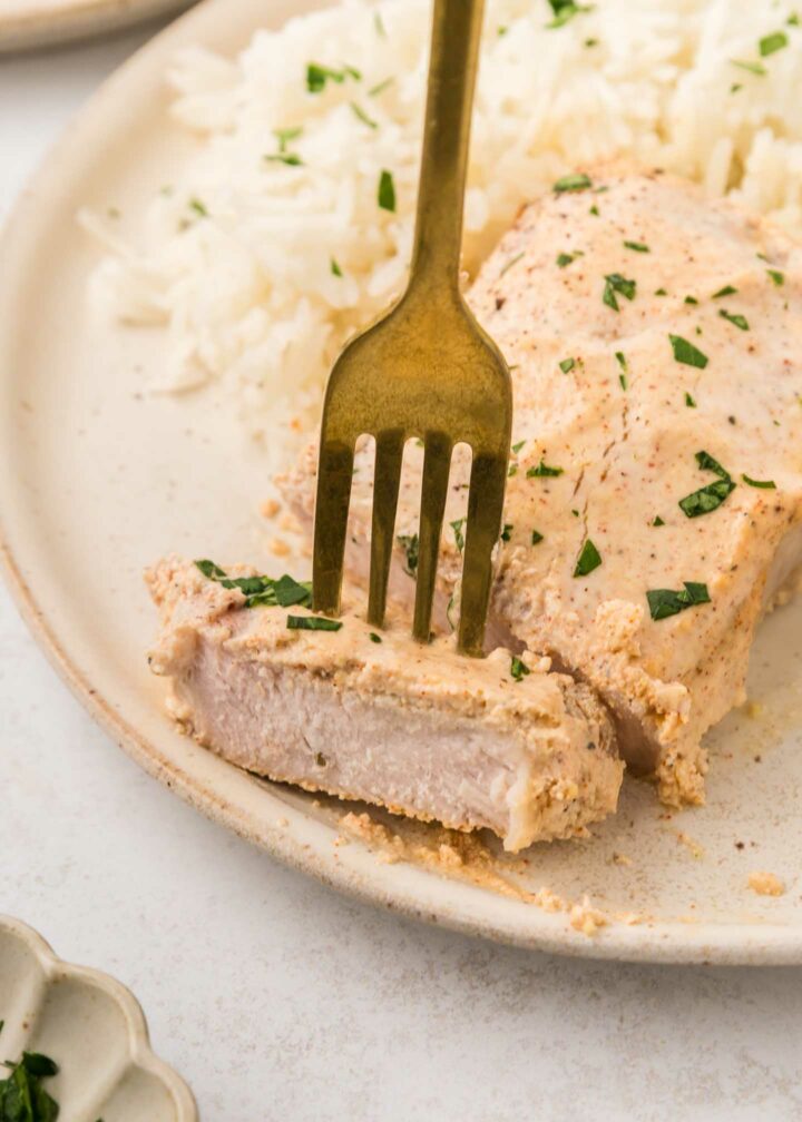 pork chop with a forkful of pork plated with mashed potatoes