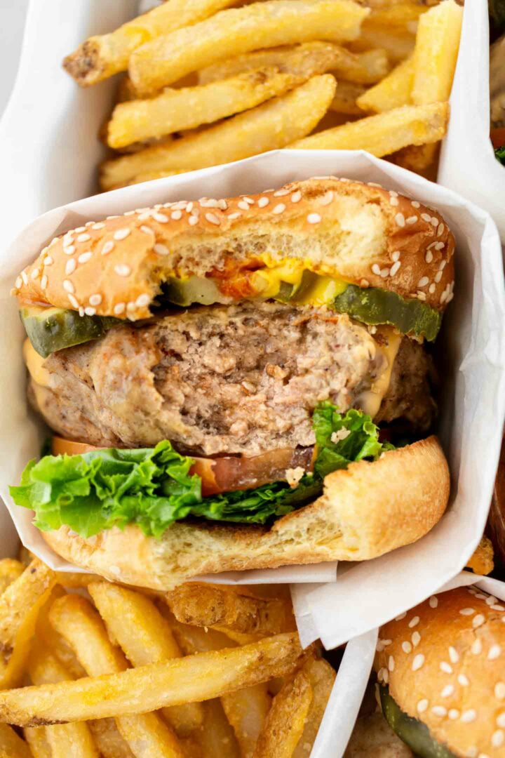 turkey burger with a bite taken out in a casserole dish with fries