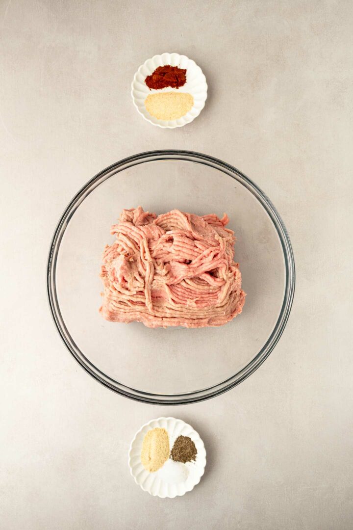 ground turkey in a glass bowl with seasonings in small dishes