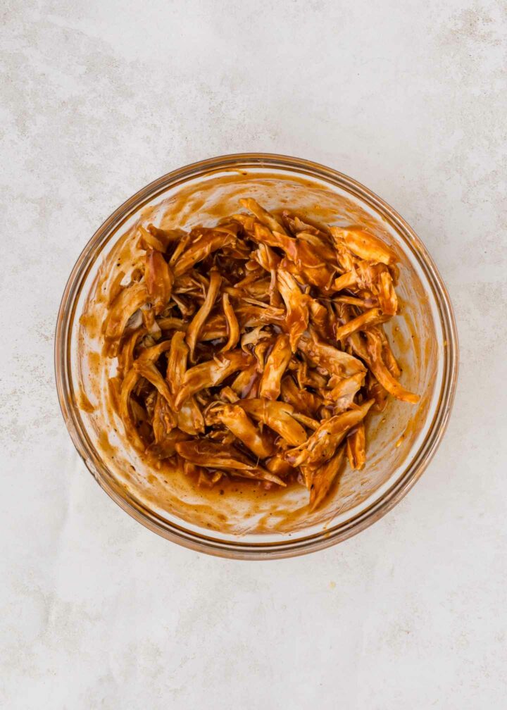 chicken mixed with bbq sauce in a clear bowl