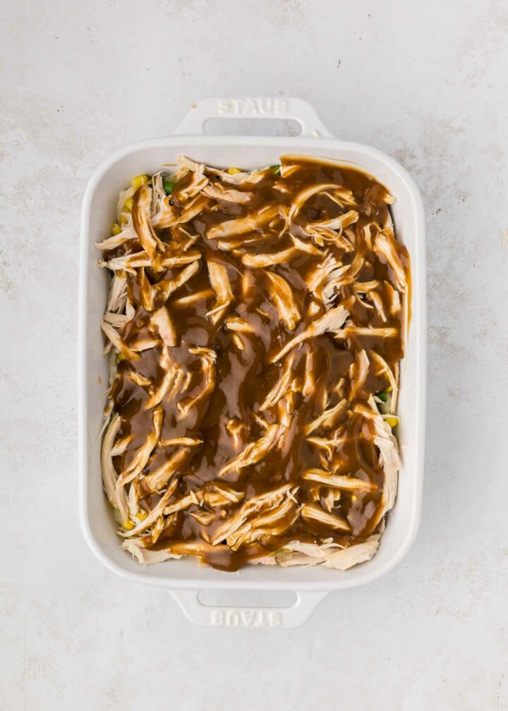 brown gravy poured over chicken in a white dish